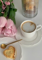 Morning breakfast with cup of coffee and biscuits in the background pink flower tulips