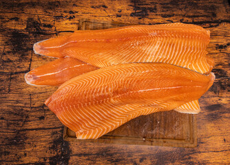 Large raw salmon fillets on a wooden board