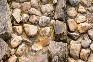 wet stones in the bottom of an artificial dry river. texture background