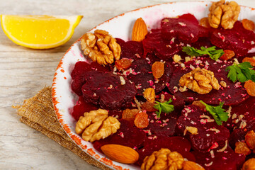 Beetroot salad with nuts raisins and lemon on light gray background. Close-up.  Healthy eating, vegetarian food.