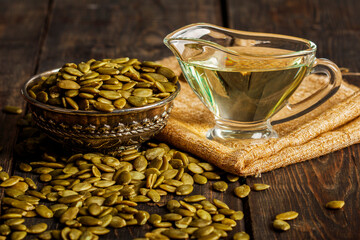 Pumpkin seed oil in a vintage dish on a wooden background. Close-up. Healthy eating pumpkin seed...
