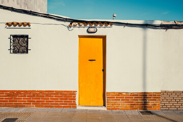 rustic yellow wooden door on a white facade