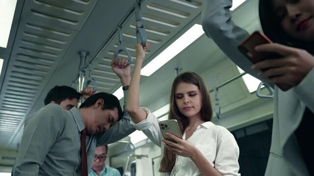 The woman was using the phone on public transport while the man standing next to Fall asleep with exhaustion after work
