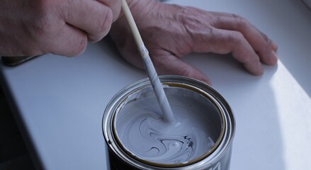 stirring paint with a color scheme until a homogeneous mass is obtained by hand with a thin stick close-up, diluting the desired shade of paint in a tin can standing on a white surface