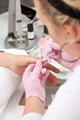 closeup of female hand getting nail manicure by professional manicurist