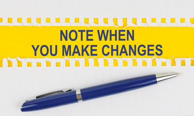 On the table are two sheets from a notebook and a pen on a yellow background written - NOTE WHEN YOU MAKE CHANGES