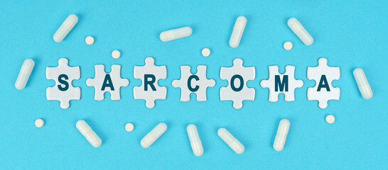 On a blue background, there are pills and puzzles with the inscription - SARCOMA