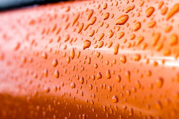 Macro of raindrops on orange car