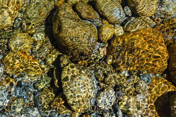 Rocks under under clear water.Water stream.Water texture.Water reflection.Summer background.