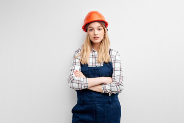 young architect business woman in orange helmet standing against white wall
