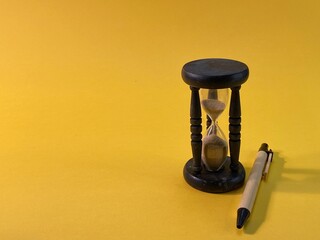 On a yellow background there is an hourglass measuring the time, next to it is a pen