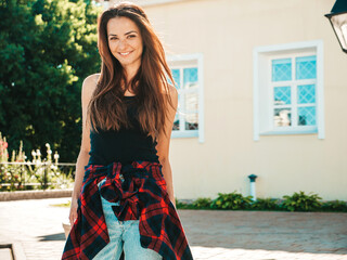 Portrait of beautiful smiling brunette model. Trendy female posing in the street background. Funny and positive woman having fun outdoors at sunset. Enjoying summer days