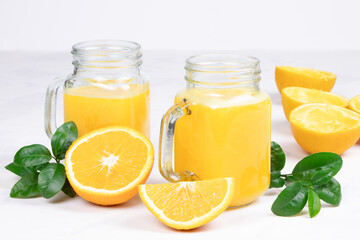 Fototapeta na wymiar Orange juice and green leaves on a white background.A glass of orange juice and orange fruit. Healthy food. Vegan food. Diet and proper nutrition. Copy space. Place for text.