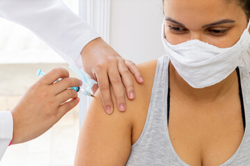 Female patient of years, with thoughtful thought, receiving vaccine on her shoulder.