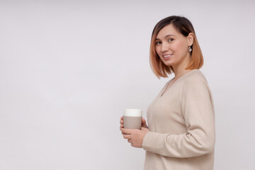Young woman holding a cup of tea while standing on a white background