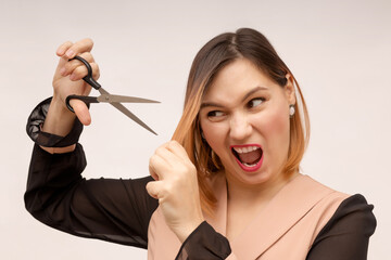Angry girl cuts her hair with scissors