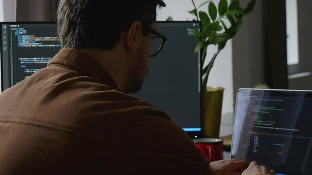 guy programmer writes code on a computer at home