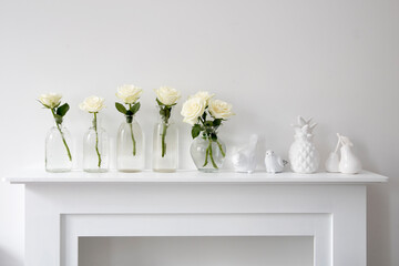 Bouquet of white roses in a glass figured vase on a white fireplace console.