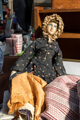 Fototapeta premium Old rag doll in a yellow hood against the background of a red woven rug