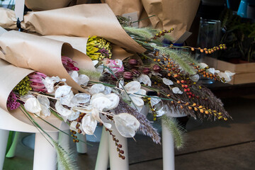 Fototapeta premium Dried flowers in bouquets in craft paper on a bench for sale