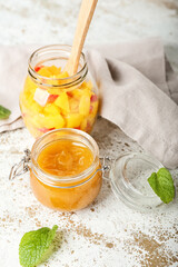 Jars with mango sauce and fruit salad on light background