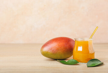 Jar with mango sauce on wooden background