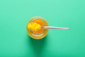 Jar with mango sauce on color background