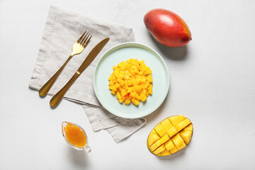 Plate with mango salad and sauce on light background