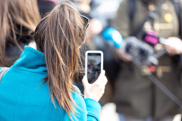 Press or news conference, mobile journalist filming media event with a smartphone