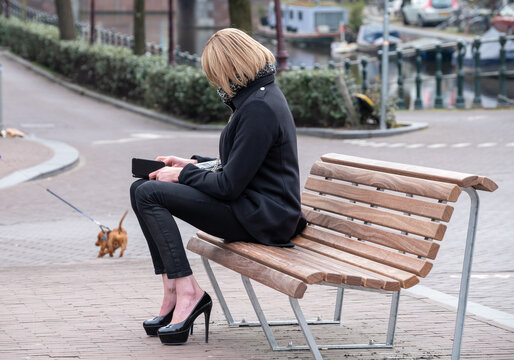 Young unindentified cross-dresser travesti man sitting on bench in Amsterdam