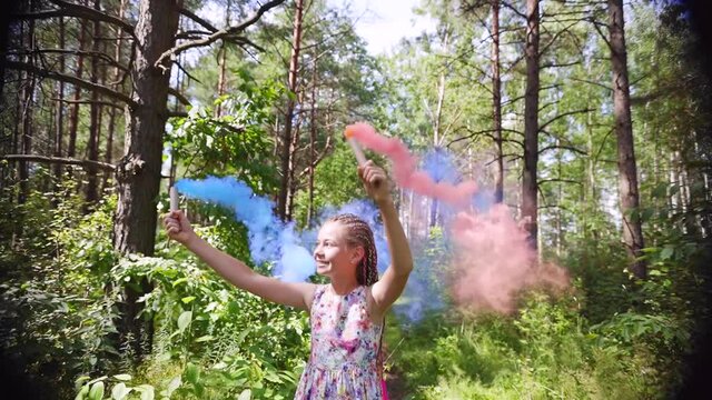 A teenager girl with colored smoke walks in the forest.