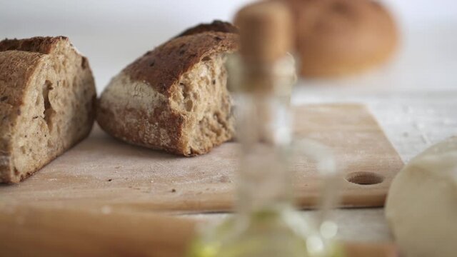 The baked bread lies on the table, the dough is prepared for baking. ingredients for cooking french loaf cereal bread. Fresh baked cereal bread lies on the table. Close-up