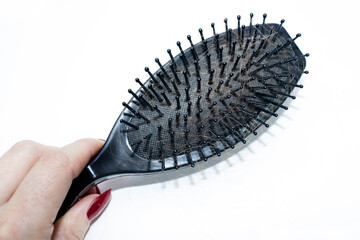 A woman's hand holds a comb with a lot of hair close-up. The concept of allopecia, hair loss, problems with the scalp