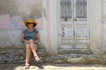 mujer con sombrero turista sentada delante de la fachada de una casa vieja almería molino de rio aguas 4M0A0019-as21 - obrazy, fototapety, plakaty