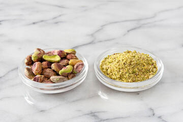 Small pile of pistachios in a saucer, whole shelled and powdered