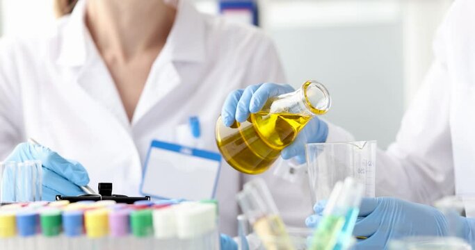 Chemist pouring oil into glass from flask 4k movie
