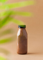 Brown smoothies in a bottle on a brown background. Sports nutrition, healthy food. Copy space.