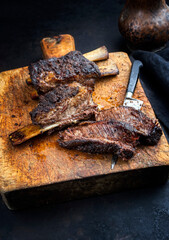 Traditional barbecue burnt chuck beef ribs marinated with spicy rub served as close-up on a rustic old wooden cutting board