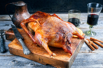 Traditional roasted stuffed Christmas goose with orange slices served as close-up on an old rustic wooden board