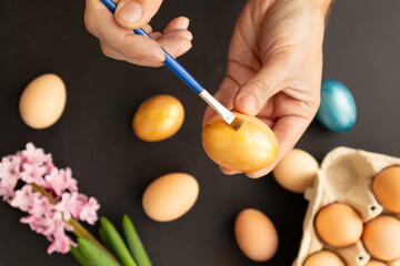 Preparing for Easter. Father painting Easter eggs on black background. Easter day.