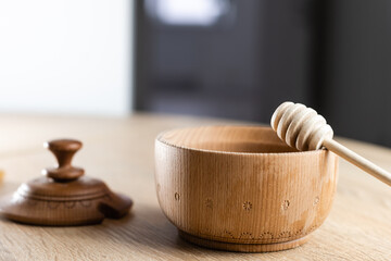 honey in a deep wooden bowl, rustic wooden plate. The wooden spoon drips slowly.