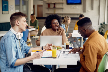 Group happy students talking while learning in cafeteria.