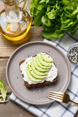 Rye bread toast with avocado and cream cheese on wooden table background. Flat lay, top view