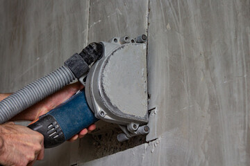 cutting a wall with a power tool at a construction site using a vacuum cleaner