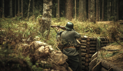 Finnish soldier of the Second World War, shooting from a trench in the forest. A steel helmet on his head and a rifle in his hands.