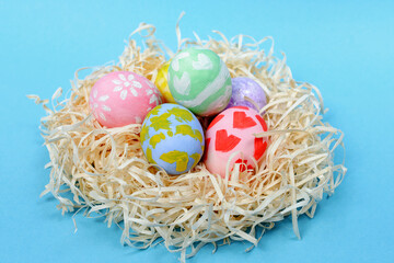 Various Easter eggs in the nest on the blue background