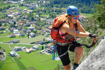 Woman climbs via ferrata route Nassereith above Dormitz village, Austria. Summer, adventure,...