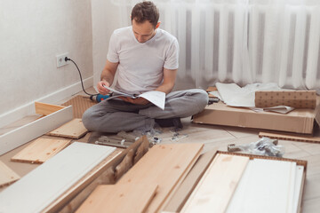 Bewildered man assembling new wooden furniture at home. Man reading instructions and misunderstand what to do the next.