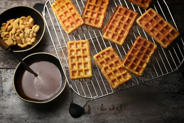 Selective focus. Fresh waffles on a wire rack, chocolate and nuts.