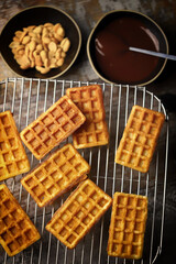 Selective focus. Fresh waffles on a wire rack, chocolate and nuts.